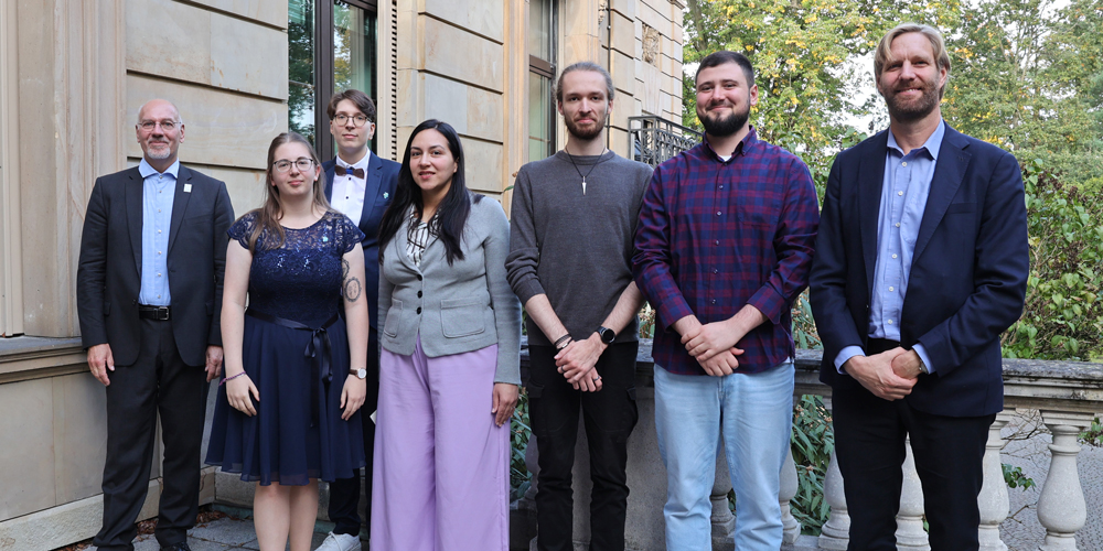 Foto: Gruppenfoto der Preisträgerinnen und Preisträger des Ravenstein-Förderpreises 2024 mit den Auszubildenden der LGB, zwischen Dirk Zellmer, Vorsitzender der Jury, und Prof. Mark Vetter, Vorsitzender der Kartographie-Stiftung Ravenstein © BKG