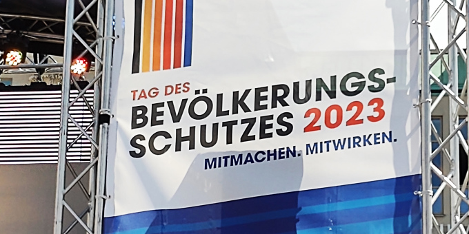 öffnet Foto und zeigt Banner mit Logo des Tags des Bevölkerungsschutzes am 24. Juni 2023